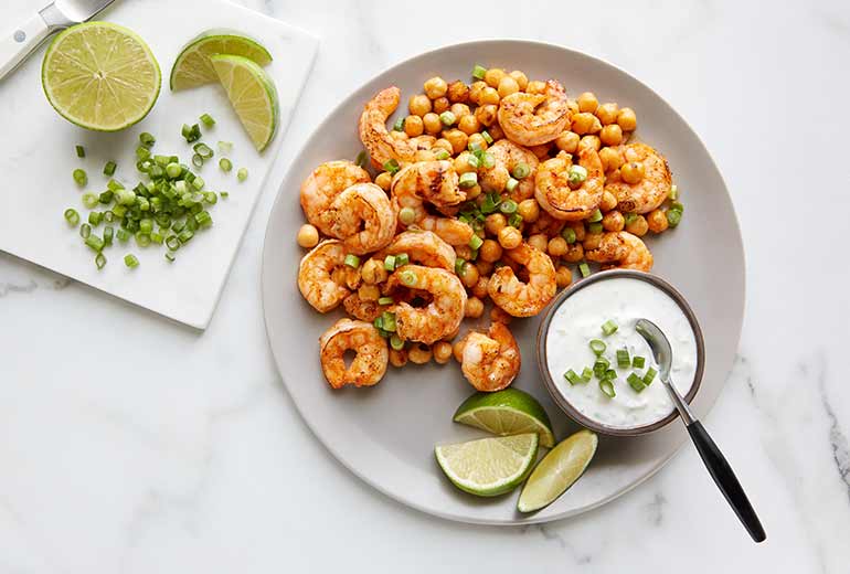 a plate of shrimp and chickpeas with lime