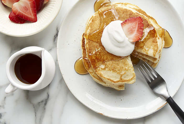 a plate of pancakes topped with strawberries